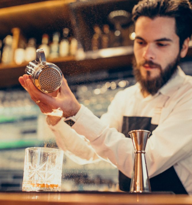 Handsome bartender making drinking and cocktails at a counter